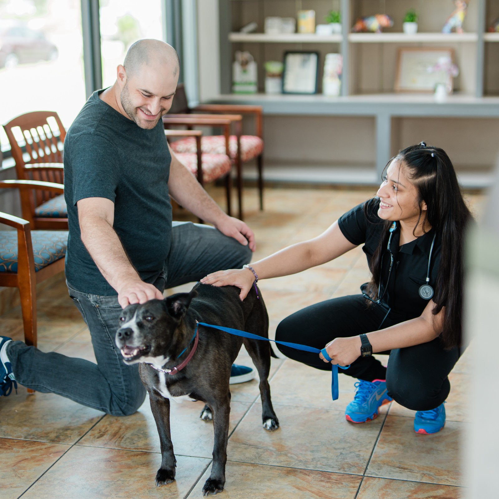 man and vet tech with a dog in the reception area