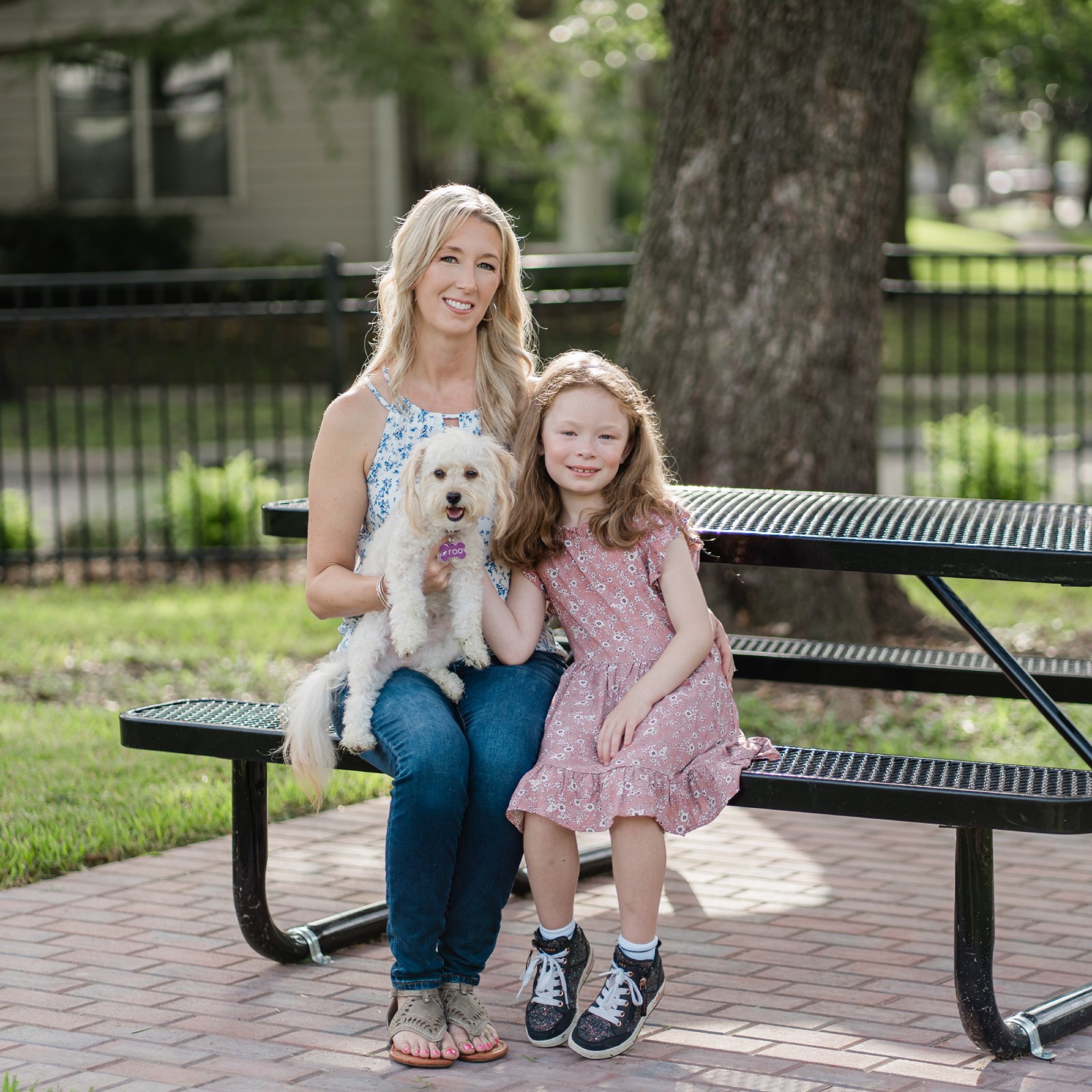 Woman, girl, and dog sitting on a park bench